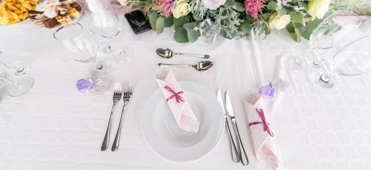 Elegant table setting with floral centerpiece, cutlery, and glasses at a wedding or event.
