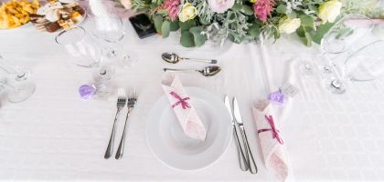 Elegant table setting with floral centerpiece, cutlery, and glasses at a wedding or event.