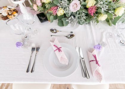 Elegant table setting with floral centerpiece, cutlery, and glasses at a wedding or event.