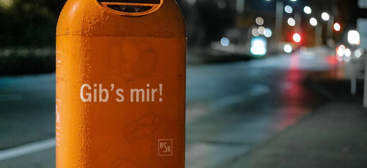 orange metal trash bin by roadside at nighttime