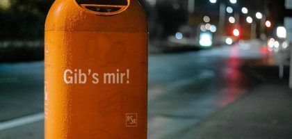 orange metal trash bin by roadside at nighttime