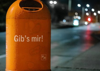 orange metal trash bin by roadside at nighttime